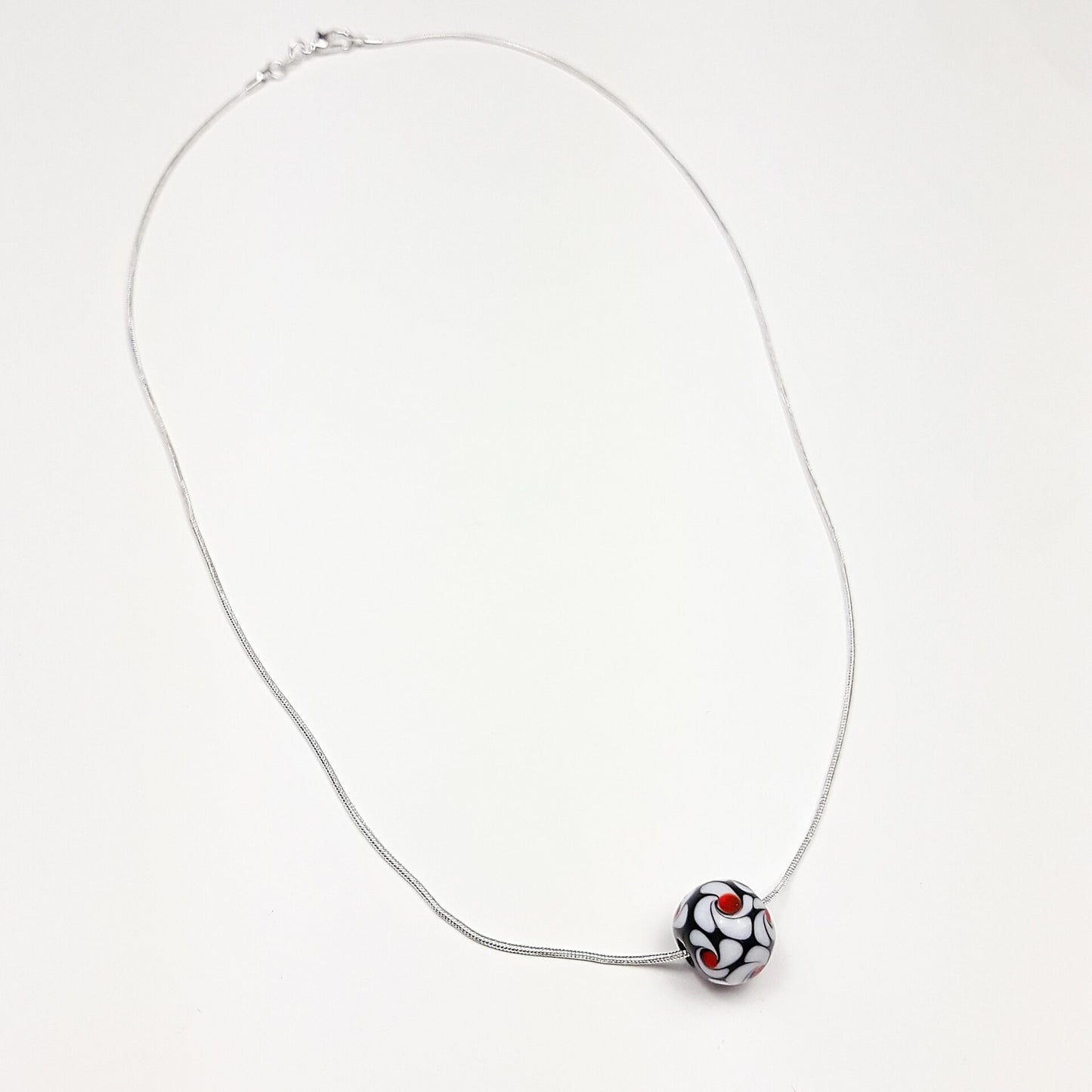 Schwarz-weiße Wirbel mit roten Akzenten - Glasperle auf Silberkette